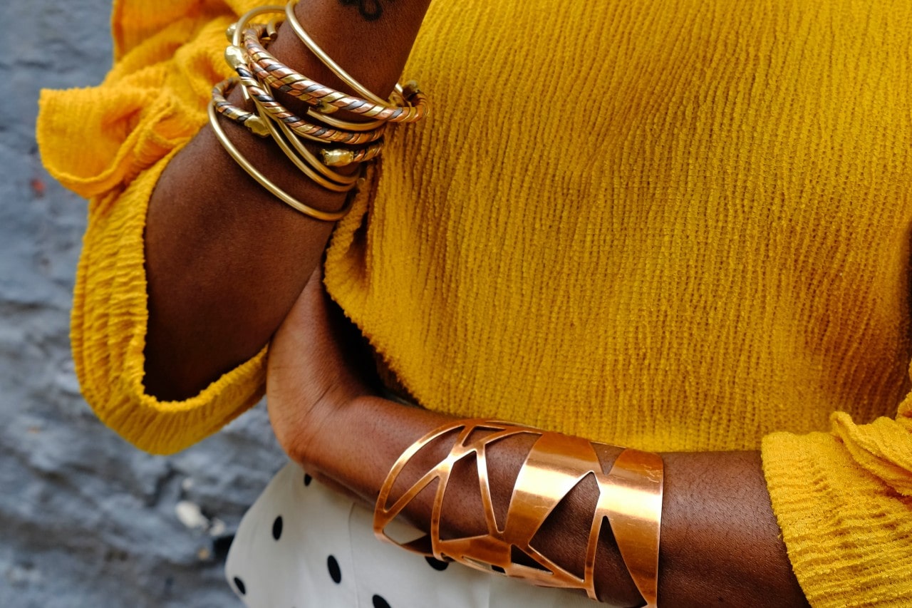Woman wearing multiple yellow gold and mixed tones bangles and cuffs