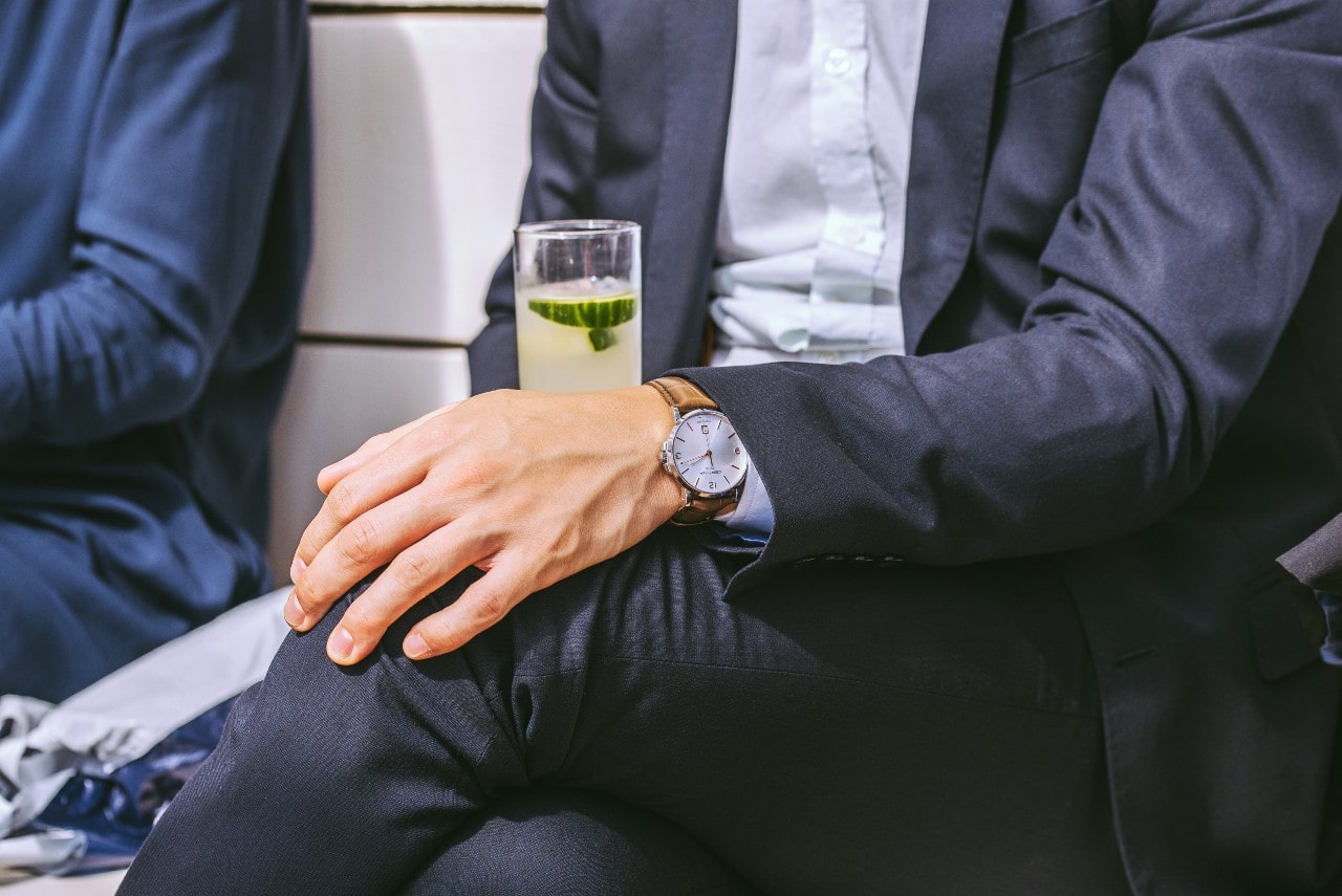 Fashionable man wearing a fancy timepiece and drinking a cucumber beverage