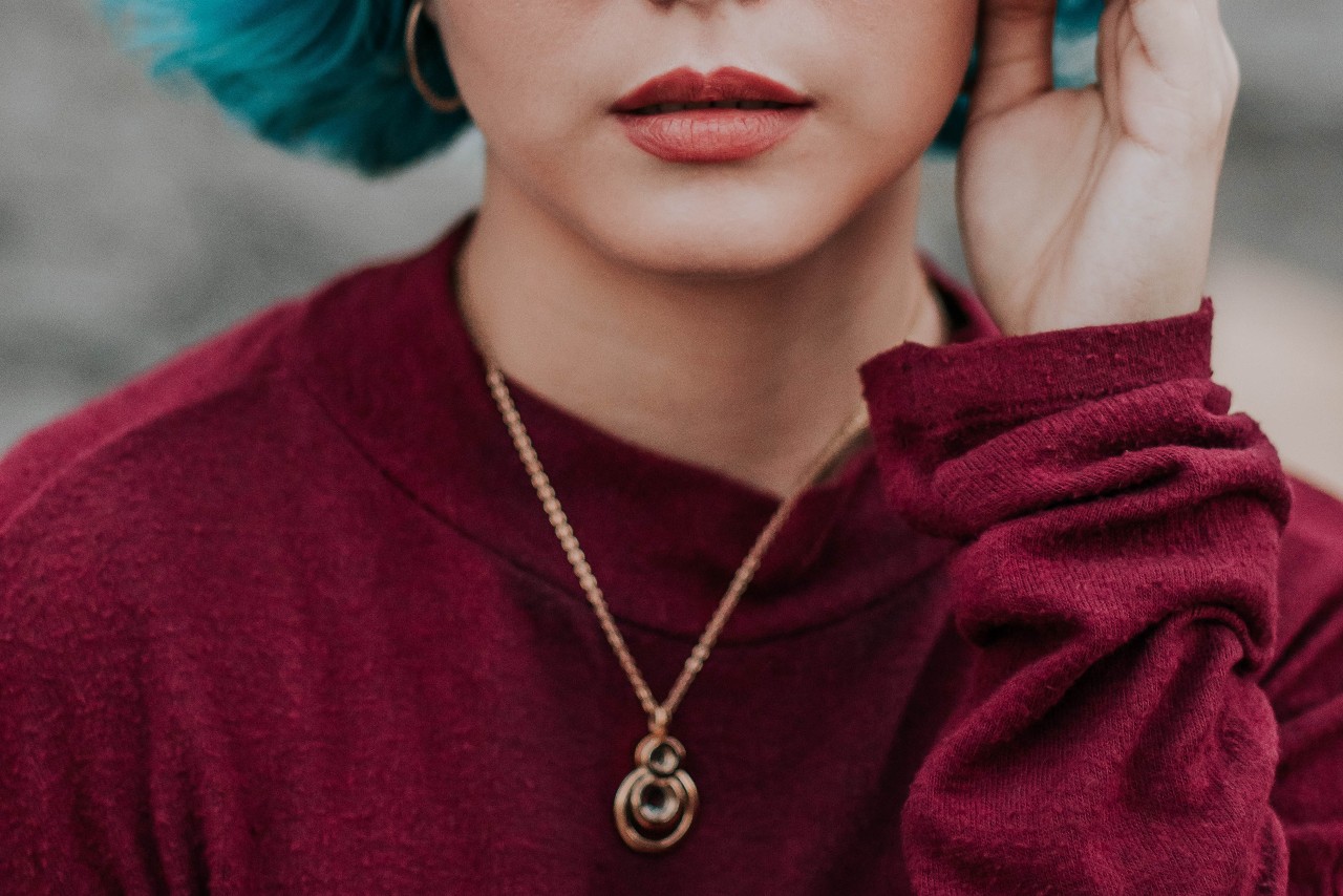 A woman wearing a maroon sweatshirt wears a gold pendant