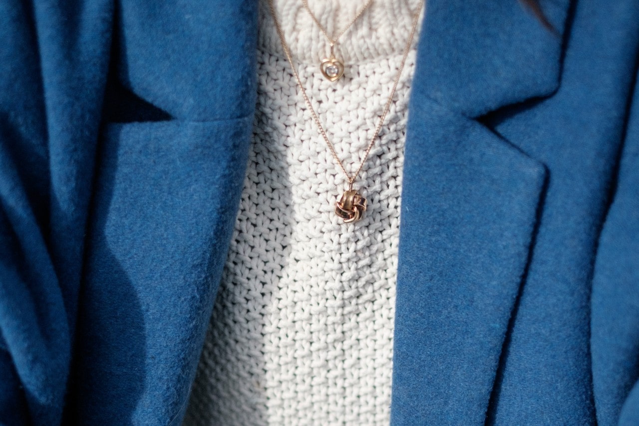 A woman wearing a blue blazer sports two gold necklaces