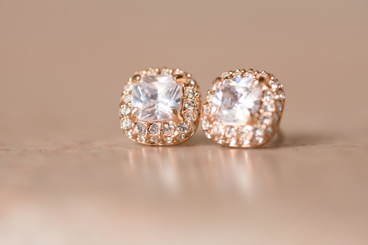 A pair of rose gold halo diamond studs feature natural diamonds