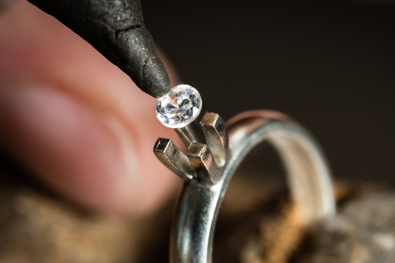 A jeweler places a round-cut lab-grown diamond into a set of prongs on a solitaire ring