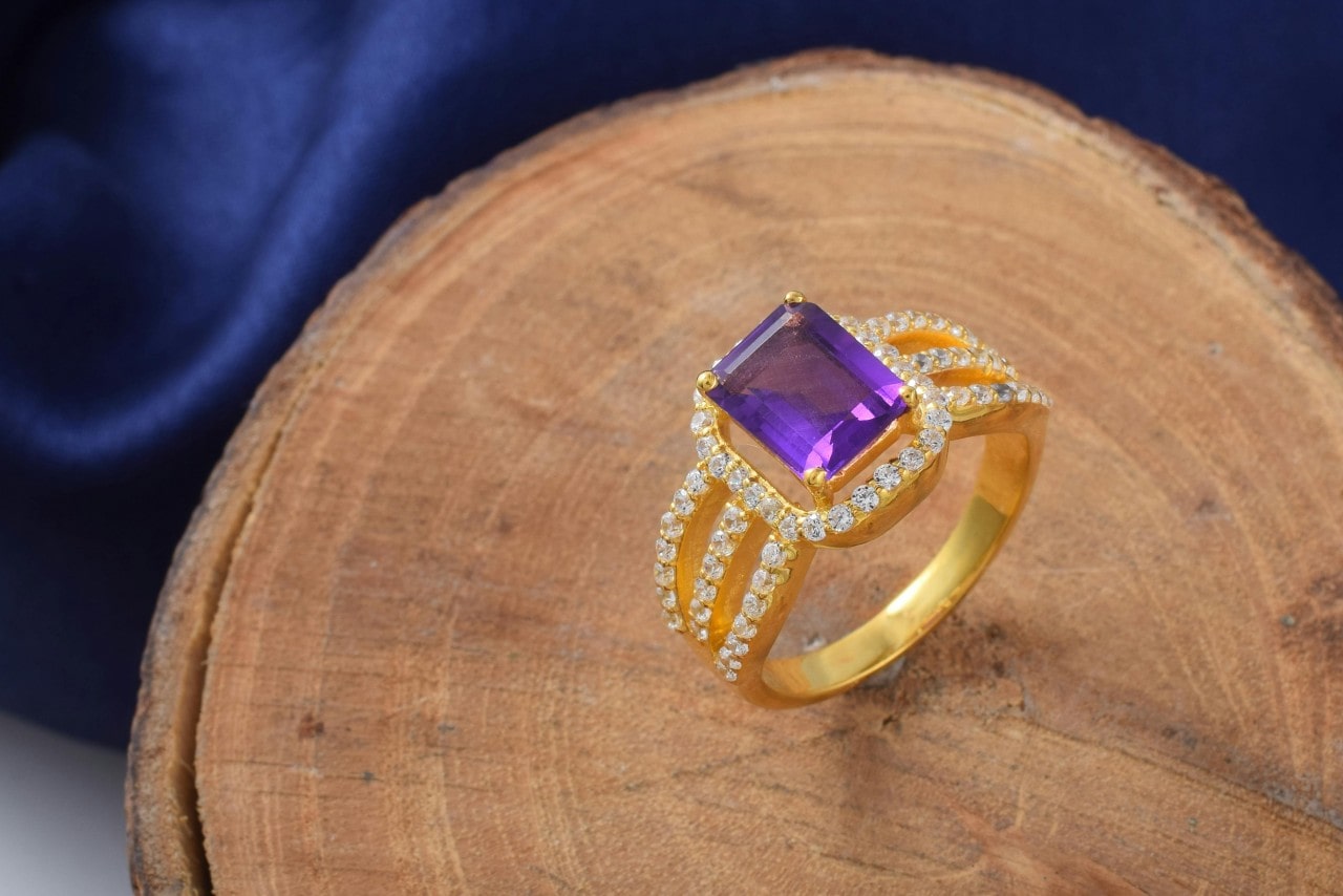 a yellow gold an amethyst fashion ring with diamond accents on a piece of wood