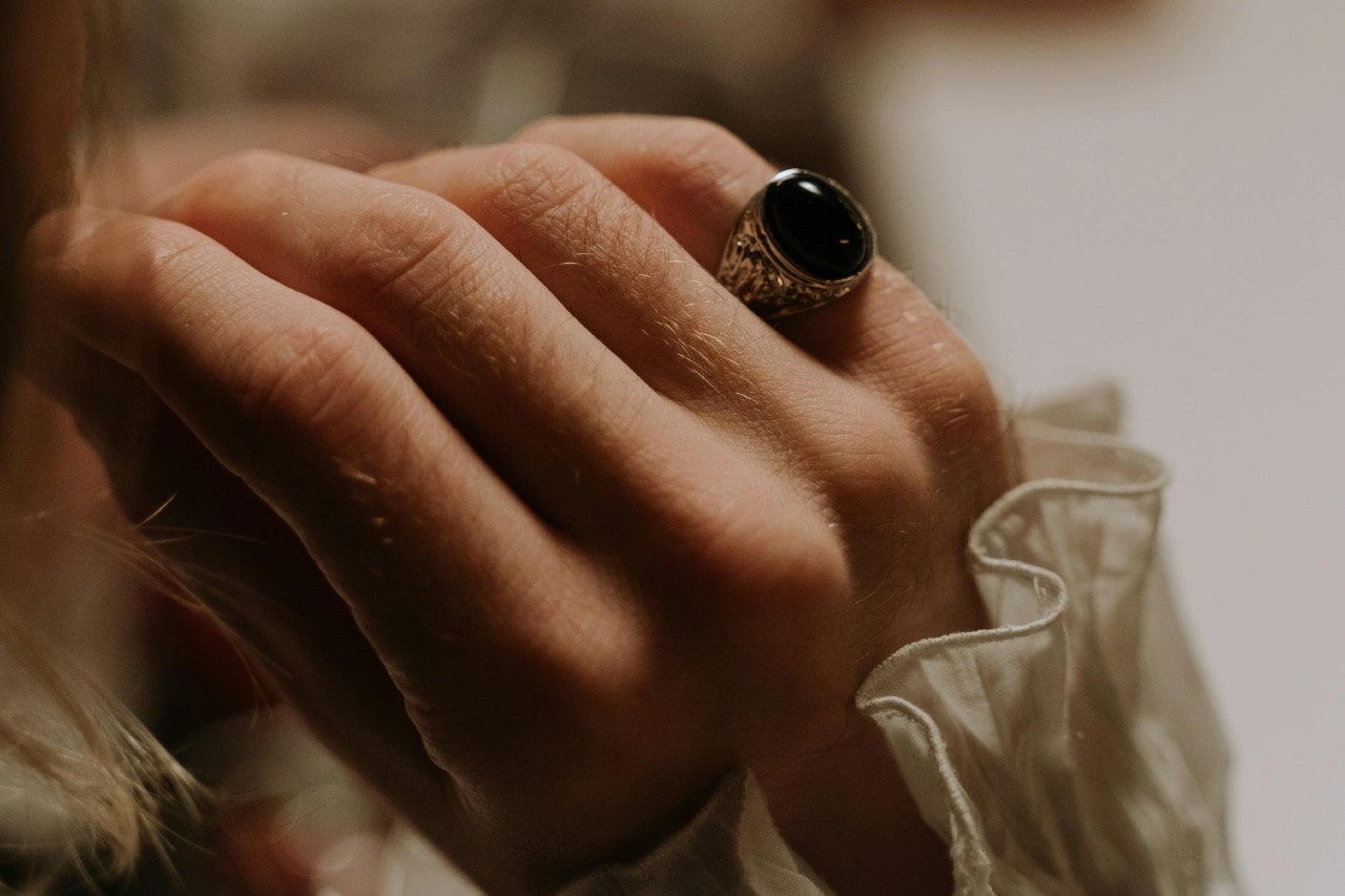 a woman’s hand adorned with a silver ring with a black stone