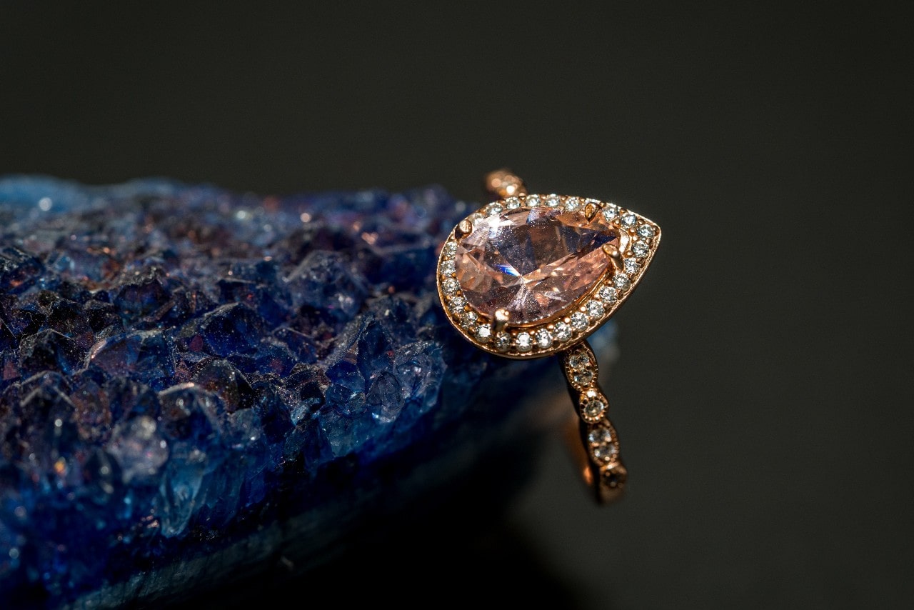 a rose gold and citrine ring with diamond accents sitting on a blue stone