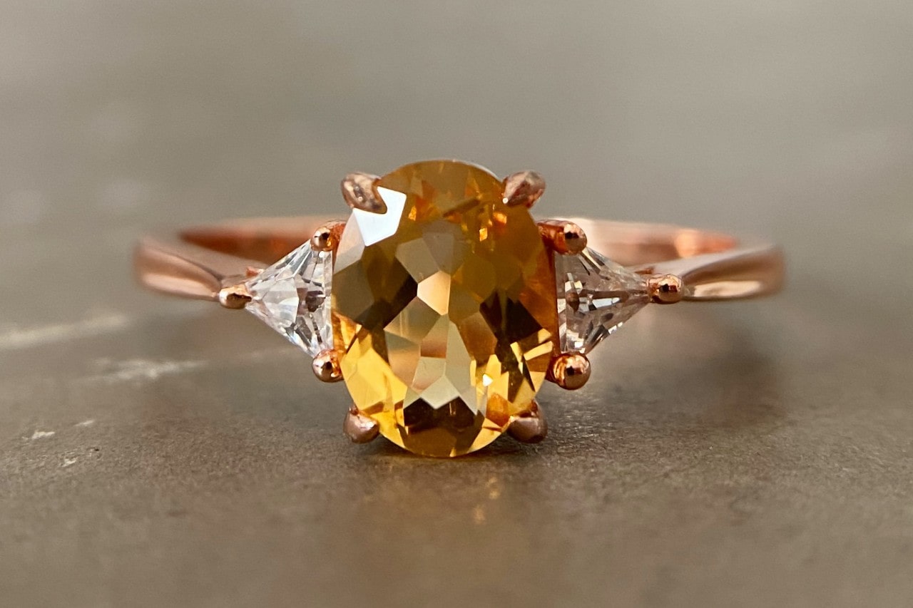 a rose gold fashion ring featuring an oval cut citrine and two accent diamonds