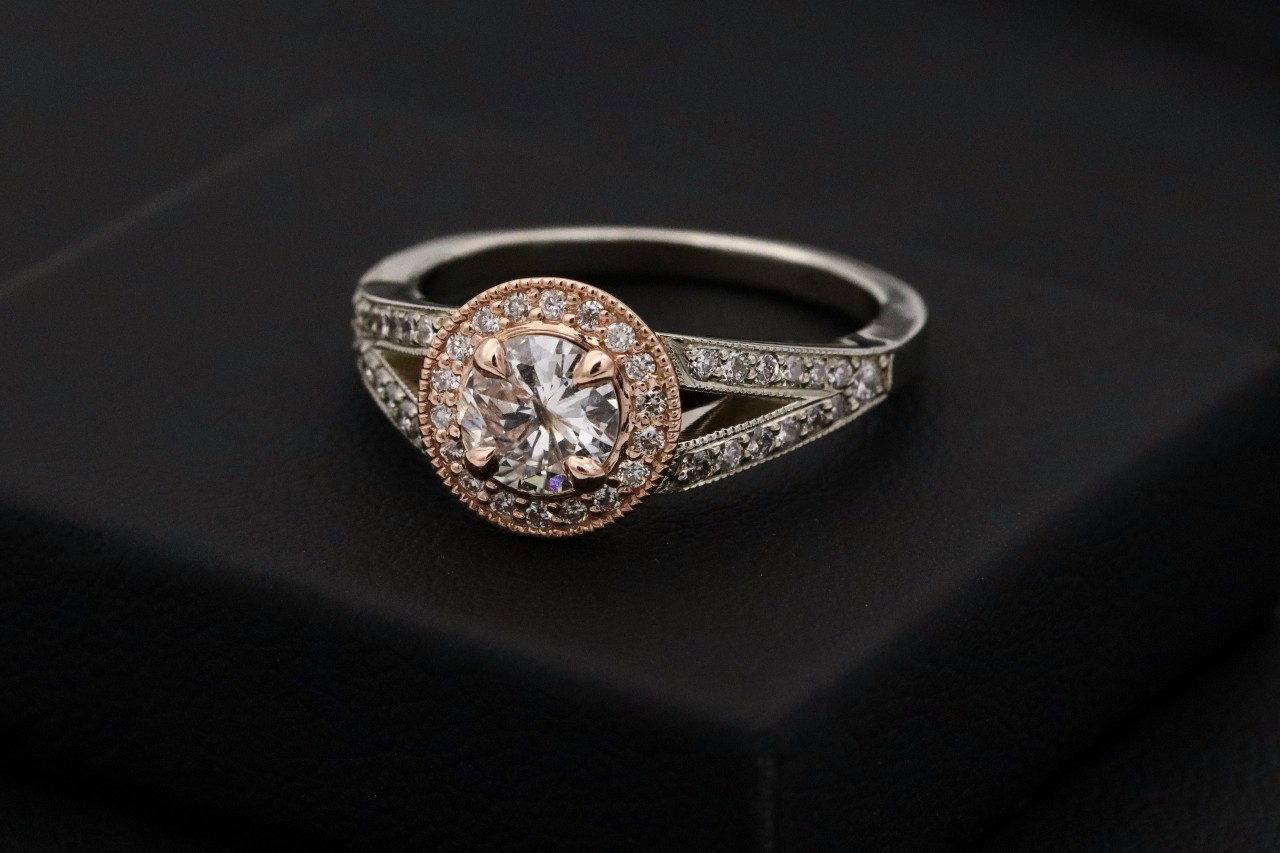 An glamorous engagement ring featuring a large center stone, a halo setting, and an ornate diamond band.