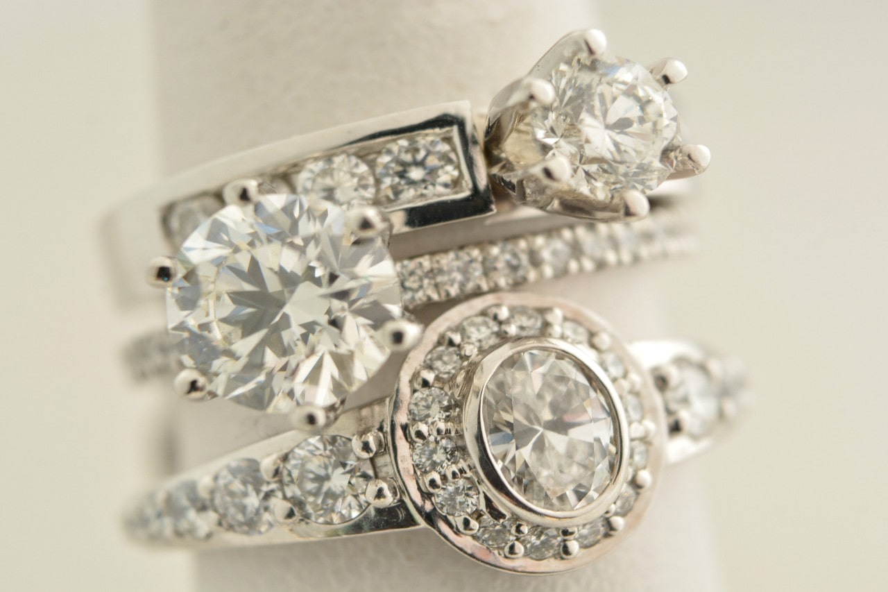 Three opulent diamond engagement rings, each featuring diamond studded bands and magnificent center stones.