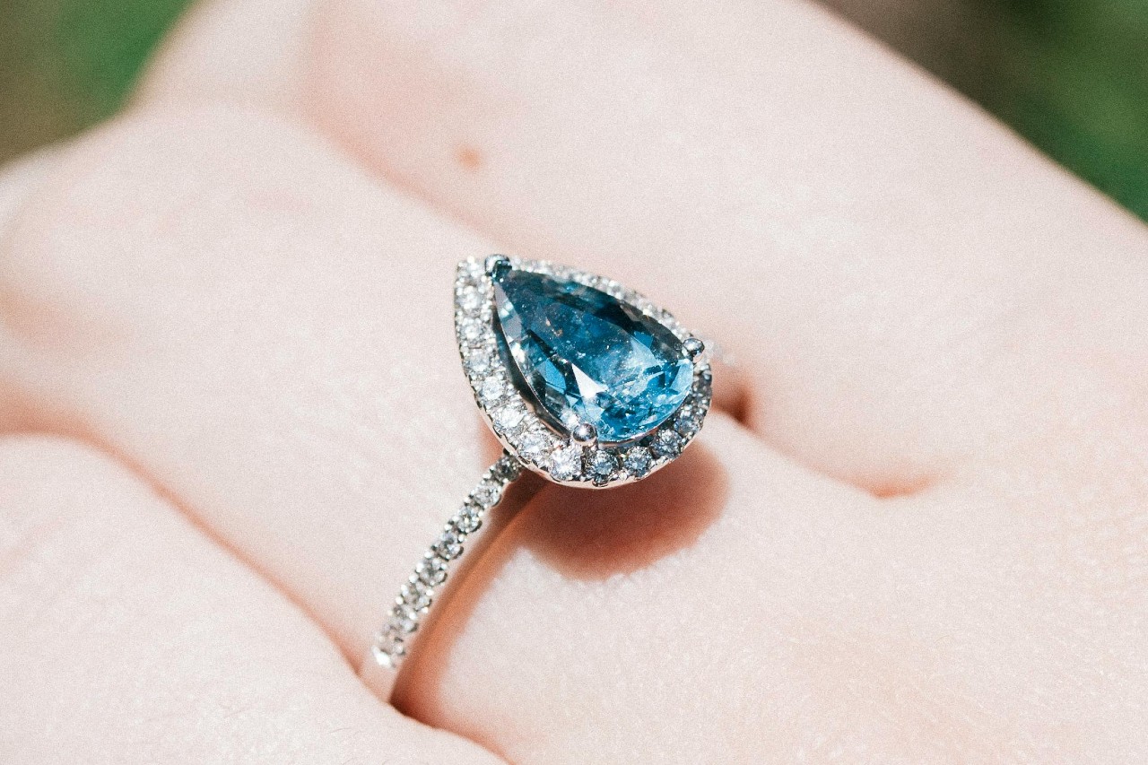 a close up image of a woman’s hand wearing an aquamarine ring