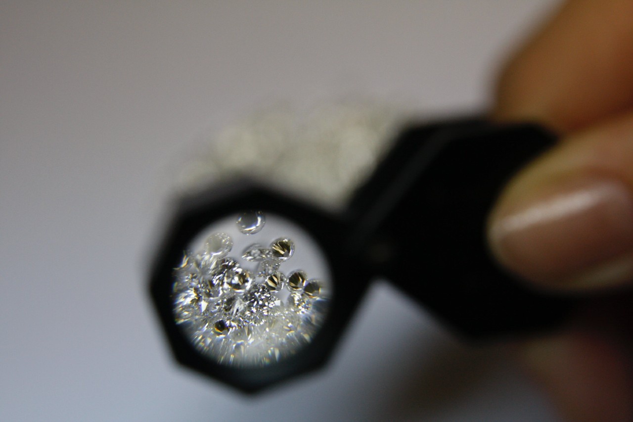 A collection of loose diamonds examined under a loupe.