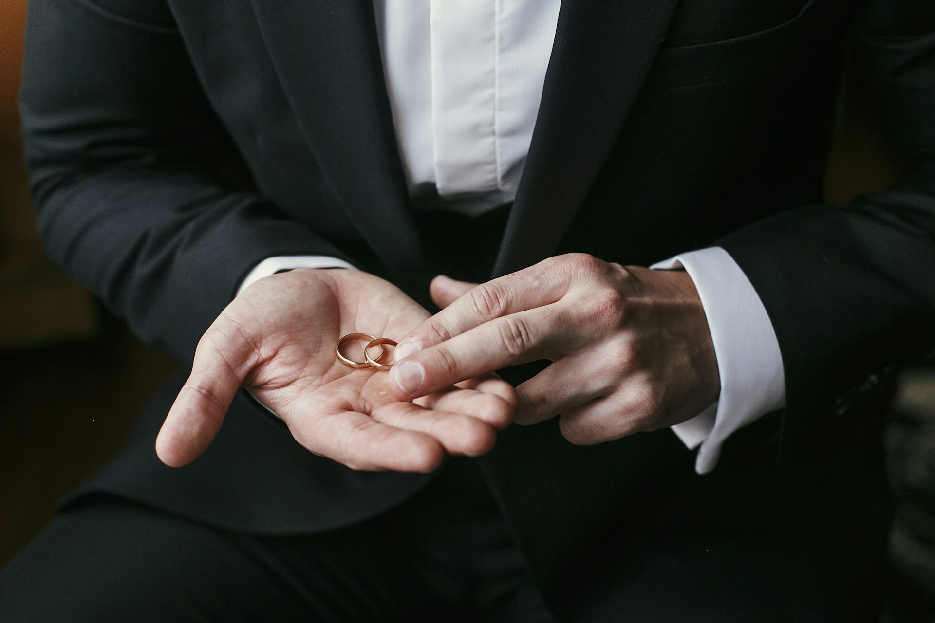 a man holding two wedding bands in the palm of his hand