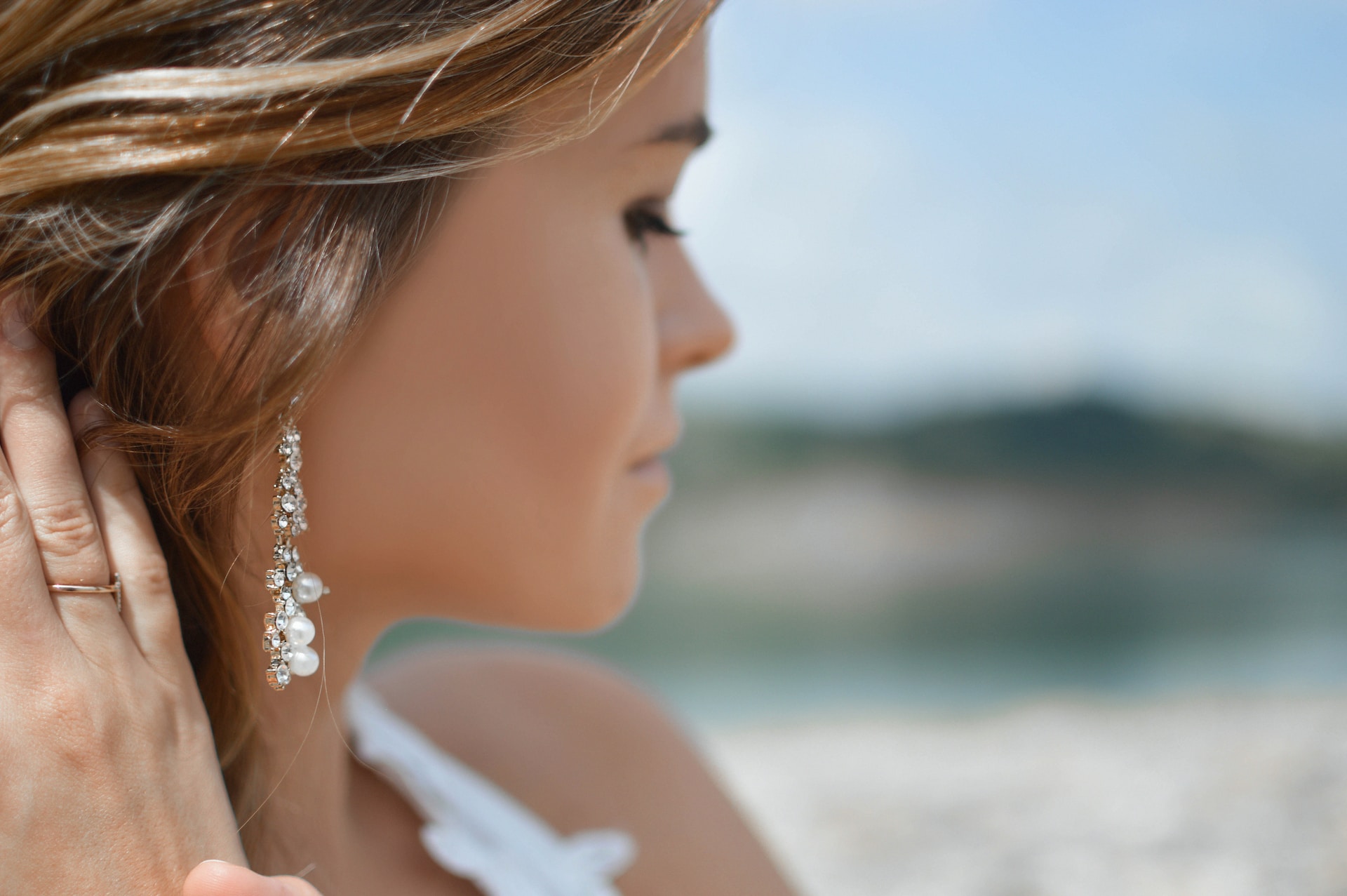 A close-up of a young woman wearing a delicate pair of diamond and pearl drop earrings. A close-up of a young woman wearing a delicate pair of diamond and pearl drop earrings.