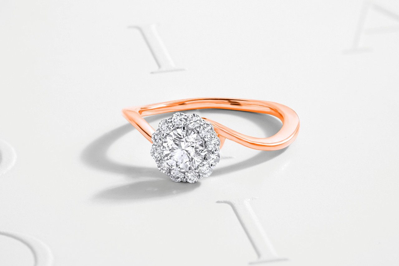 A close-up of an elegant halo engagement ring with a distinctive rose gold band.