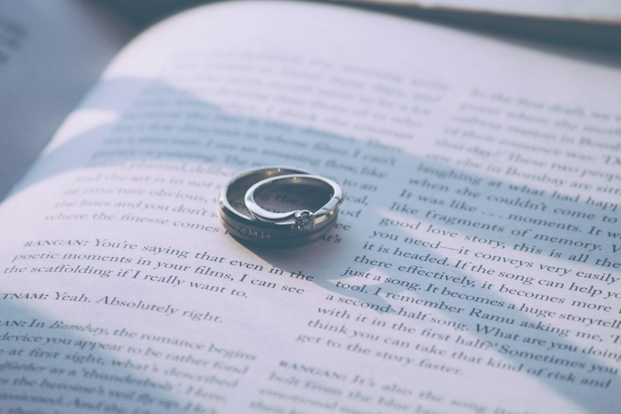 a wedding band and an engagement ring sitting together on the page of an open book