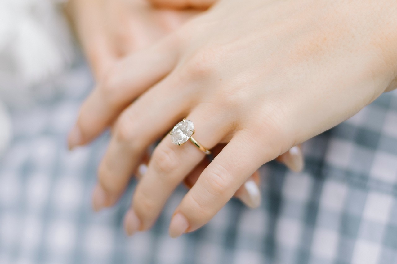 a lady’s hand wearing a simple engagement ring